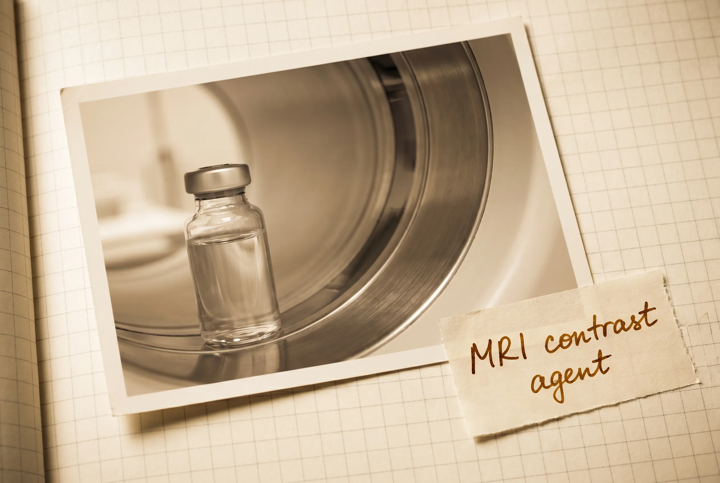 Clear vial of colorless solution beside the bore of a cylindrical MRI scanner.