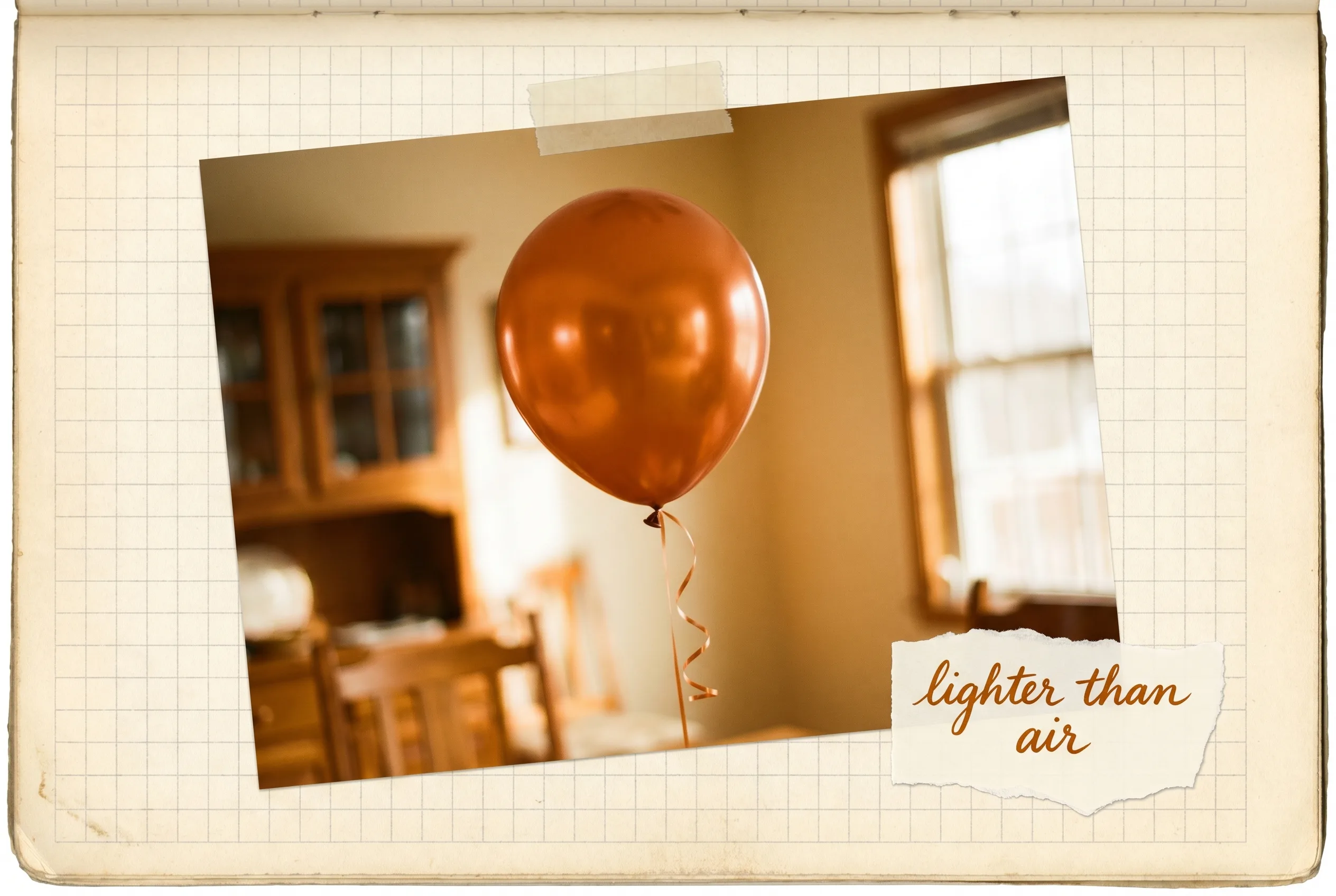 A shiny round party balloon on a ribbon floating upward indoors.